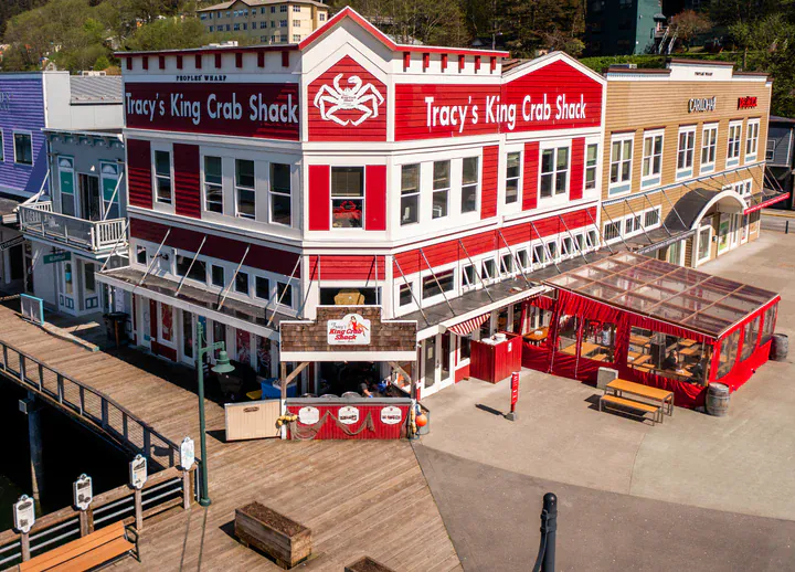 Bustling outdoor restaurant with red umbrellas and happy customers eating crab